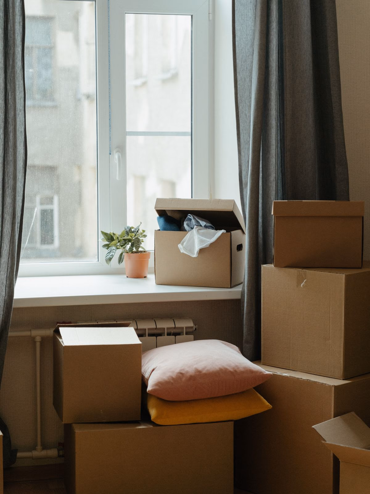 Packade flyttkartonger vid ett fönster i en lägenhet