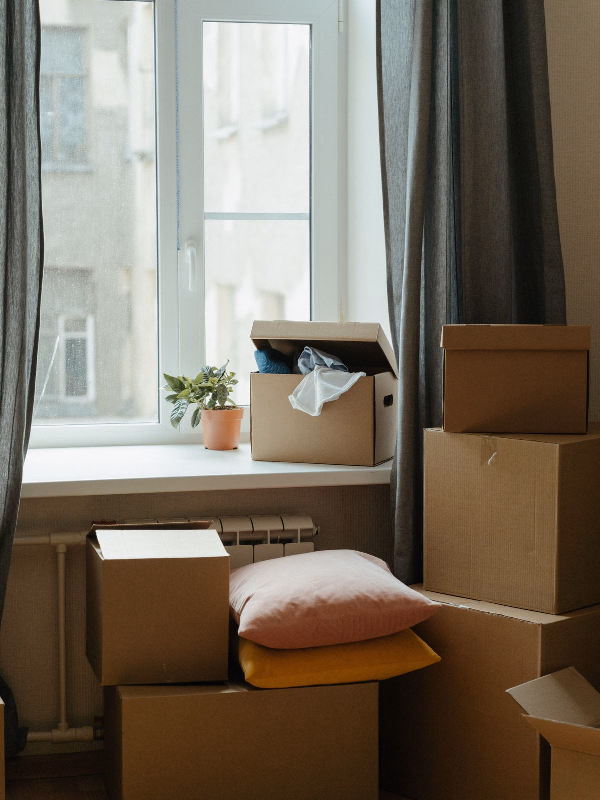Packade flyttkartonger vid ett fönster i en lägenhet
